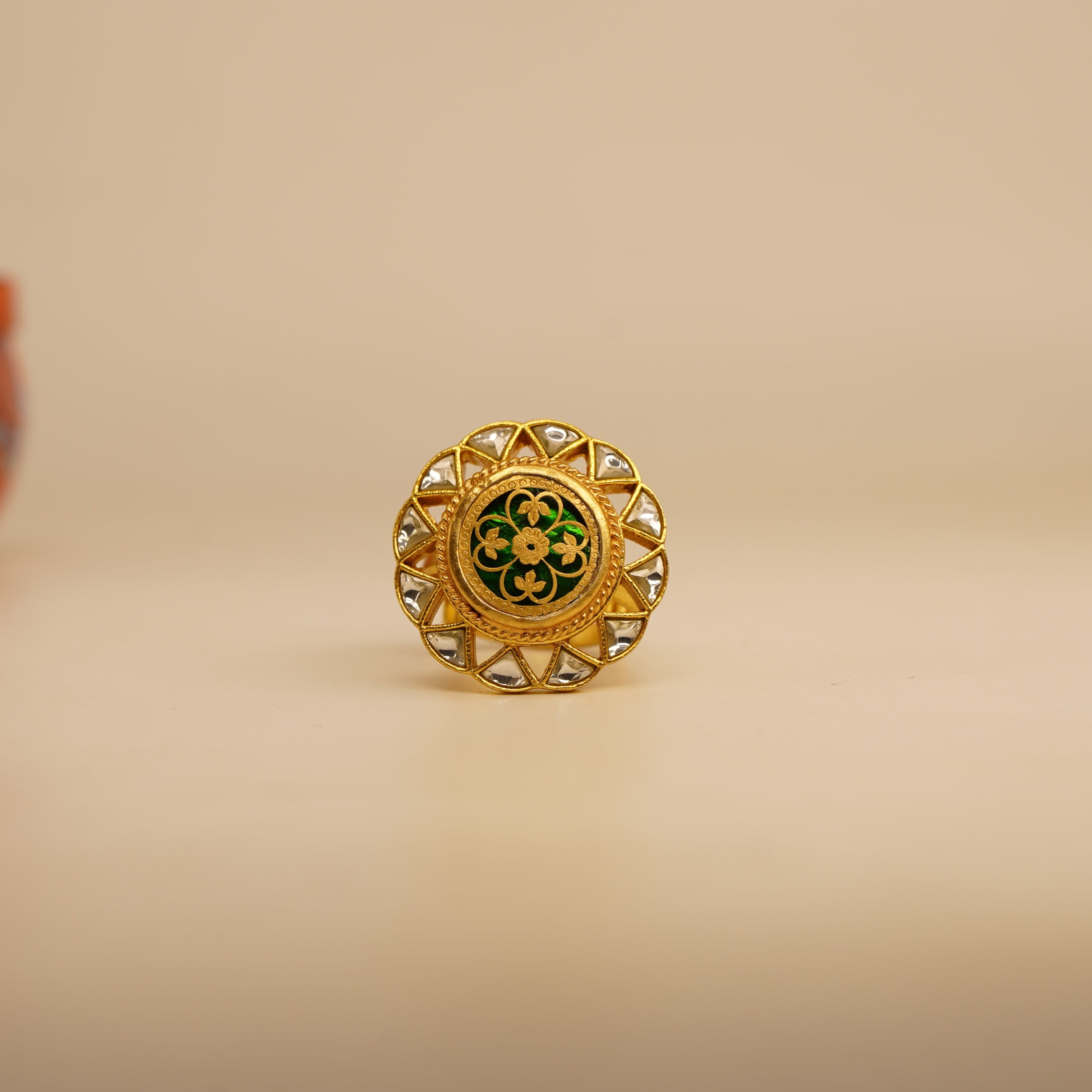 Gold ring with green gemstone on a beige background