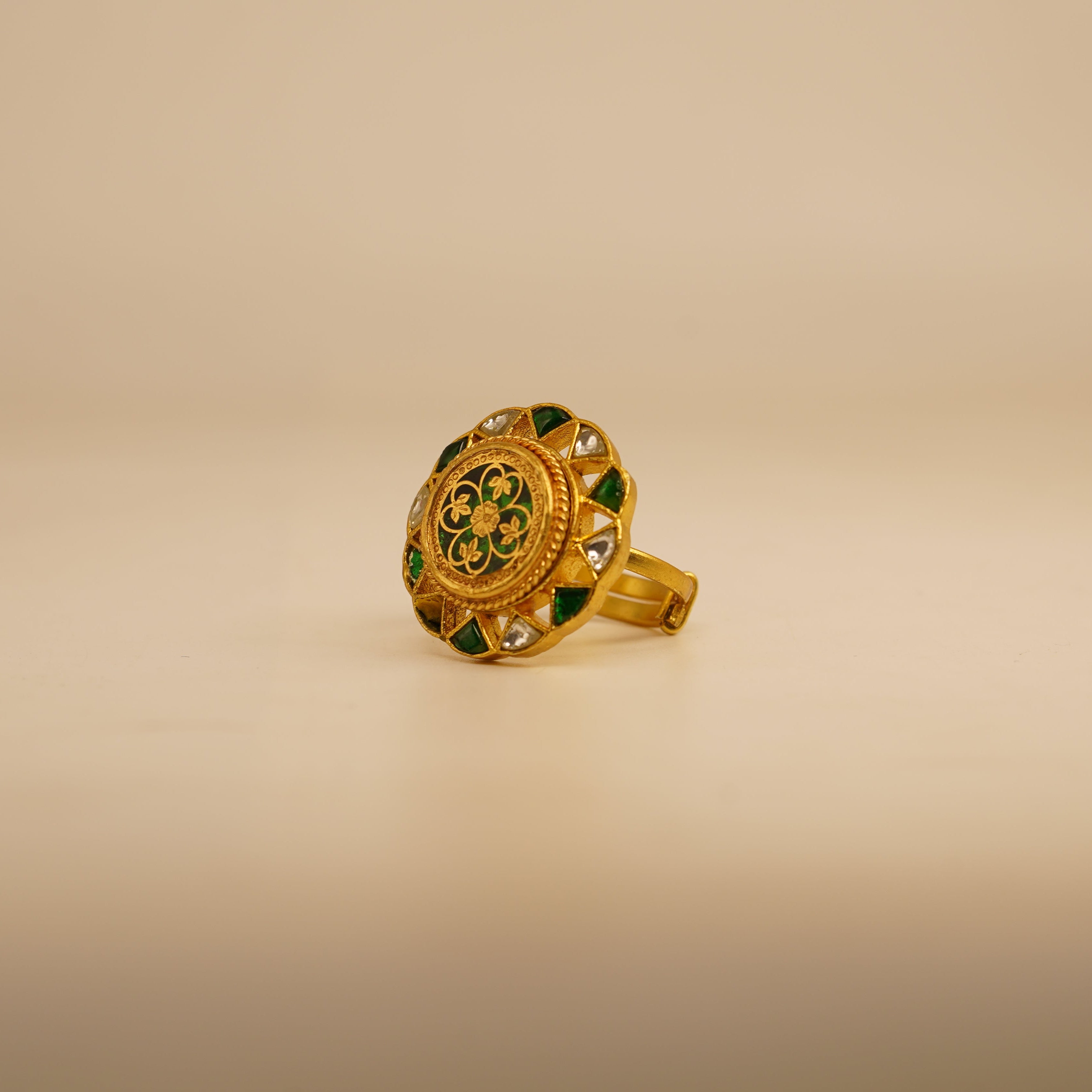 Gold ring with green gemstones on a beige background