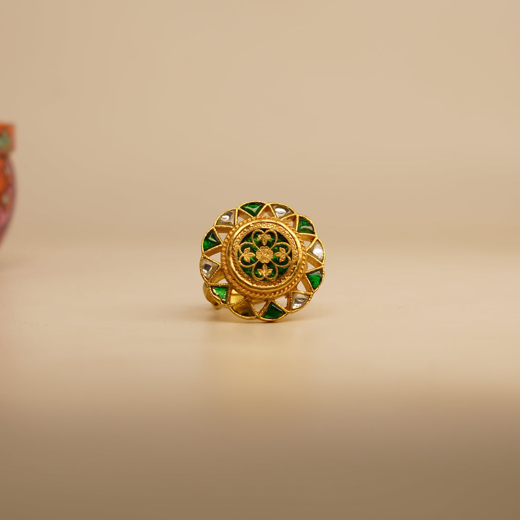 Gold ring with green gemstones on a beige background