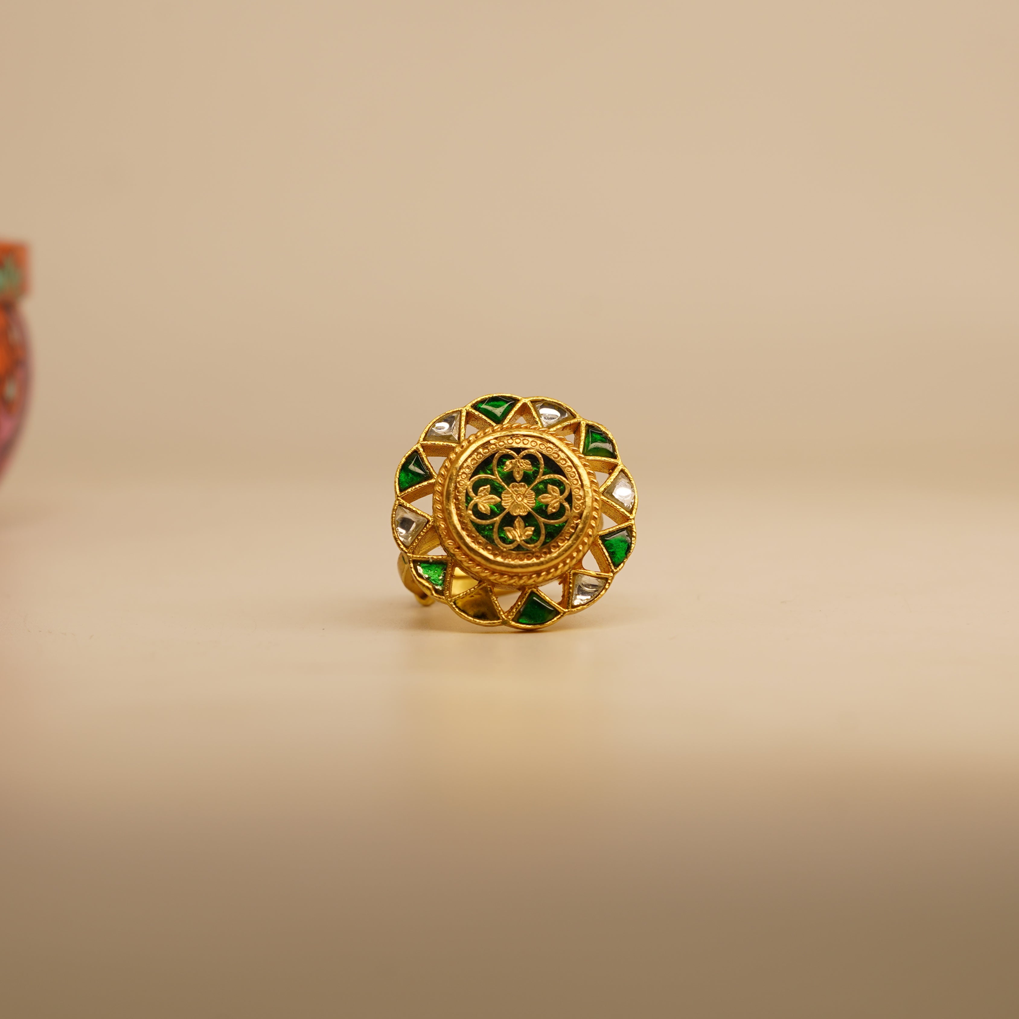 Gold ring with green gemstones on a beige background
