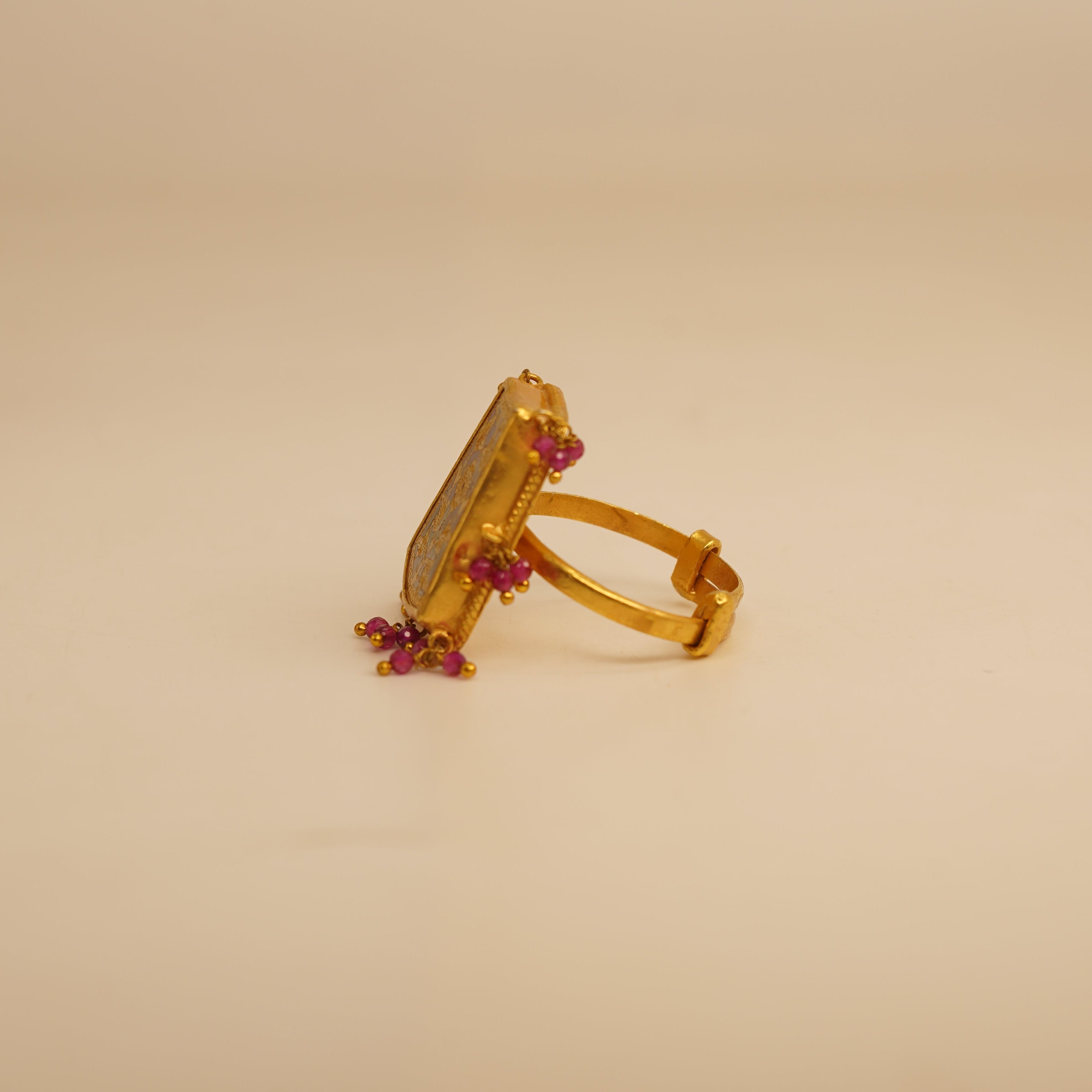 Gold ring with red gemstones on a beige background