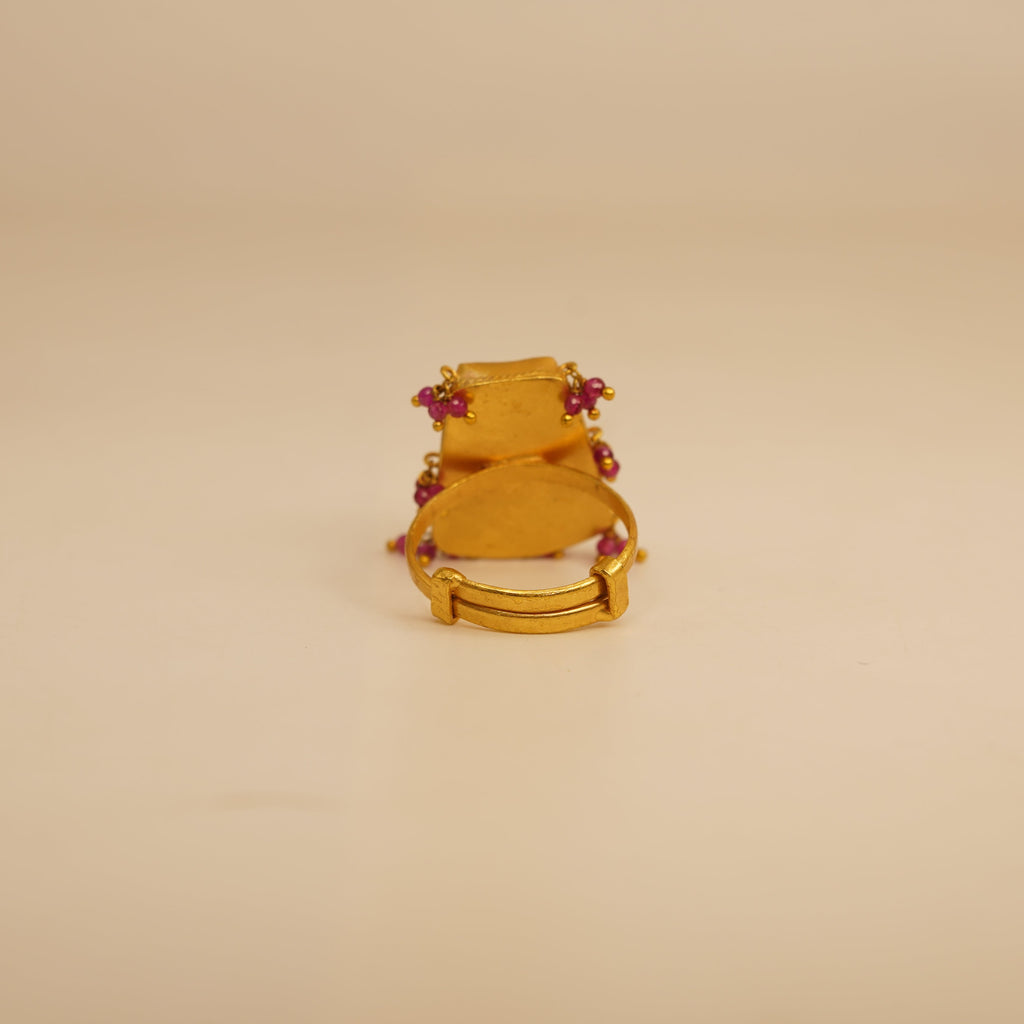 Gold ring with red gemstones on a beige background